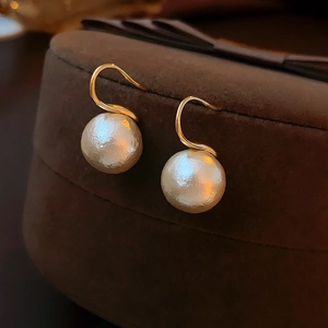 Gros plan de boucles d'oreilles en perles dorées sur une boîte à bijoux en velours brun