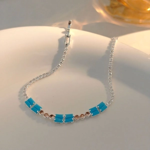 Detailed shot of silver bracelet with sky blue rectangular gems on a white plate
