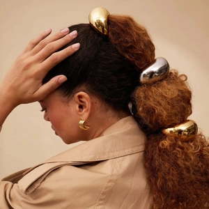 Glossy gold and silver stainless steel hair ties shown on model in a stylish ponytail