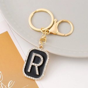 Detail of a gold letter R keychain with black enamel and sparkling rhinestones