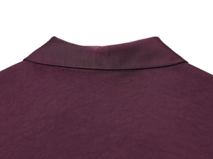 Détail macro du col d'une chemise en satin fuchsia montrant la texture du tissu