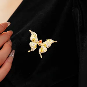 Sparkling butterfly brooch plated in gold with zircon crystals on black velvet background