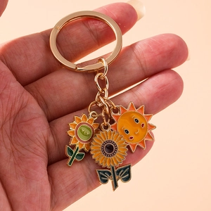 Handheld view of a pastoral sunflower bee keychain with yellow enamel flower charms