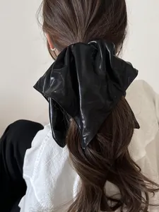 Close-up of a large black faux leather scrunchie worn on a ponytail for hair styling