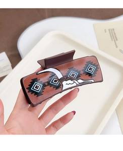 Detail of large brown rectangle hair claw clip with colorful geometric poker patterns