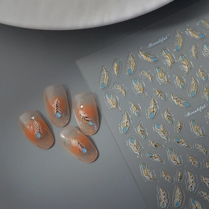 3D feather nail stickers with gold foil accents on almond nails in pastel blue and pink