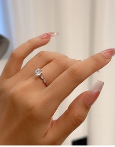 Close-up of S925 silver moissanite ring with six-prong setting on female finger