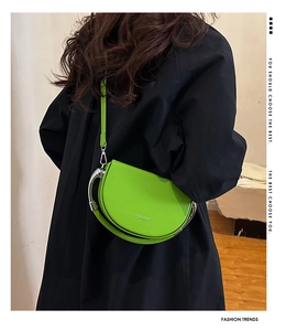 Fashionable fluorescent green crescent crossbody bag styled with a dark winter coat