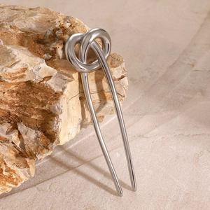 Detail of silver stainless steel knot hair pin resting on a natural textured rock