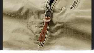 Detailansicht des Metallreißverschlusses der Khaki-Jacke mit braunem Leder-Outdoor-Puller