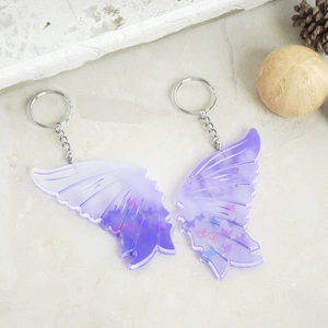 Detail of purple gradient resin butterfly wing keychains with glitter on stone surface