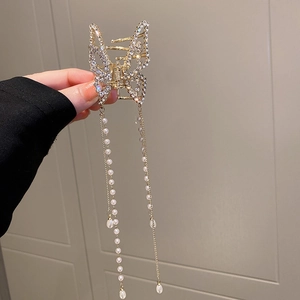 Detail of gold butterfly hair claw clip with rhinestones and long pearl tassel chains