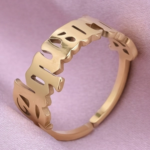Detailed macro view of a gold gothic open ring on a soft pink silk background