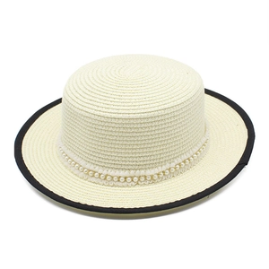 Detailed close-up of white straw boater hat with black rim and elegant pearl chain trim