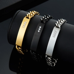 Three-tone stainless steel Cuban bracelets with cubic zirconia bar detail on black display