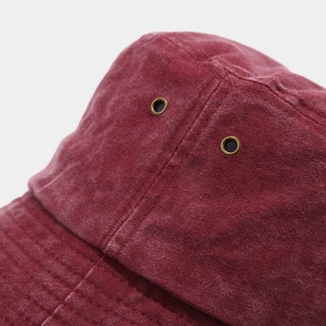 Close-up of burgundy canvas sun hat showing brass eyelets and reinforced stitching