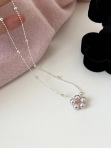 Détail macro du pendentif fleur en perles mauves et de la chaîne à billes argentée