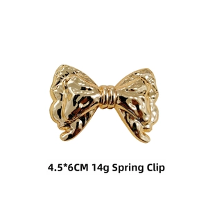 Detail of a 4.5x6cm gold bow spring clip with hammered metal texture and 14g weight