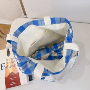 Detail of blue and white checkered canvas tote bag with zipper closure and inner pocket