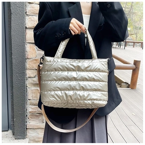 Model wearing a metallic silver puffer tote bag featuring quilted space cotton texture