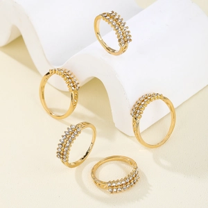 Detailed macro view of five gold rings set with double-row crystals and hollow side patterns
