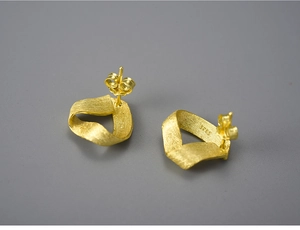 Macro shot of twisted gold ribbon earrings in S925 silver with a matte brushed finish