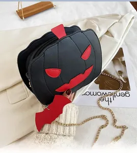 Detail of a black pumpkin shaped handbag with a red bat pendant and a gold chain strap