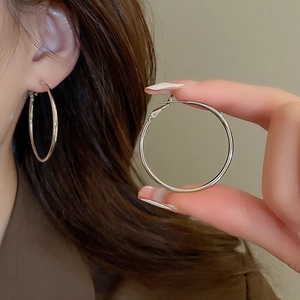 Close-up of classic silver hoop earrings showing high-shine metal finish and model fit