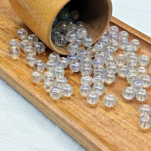 Rainbow iridescent glass round beads spilling from a wooden tube for DIY jewelry