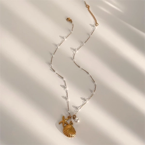 Golden starfish and scallop pendant necklace with pearls on a summer shadow background