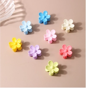 Close-up of small matte flower hair claws in eight vibrant macaron colors on beige