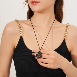 Close-up of black flower pendant necklace with tiger eye stone on a model wearing black