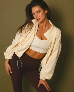 Detail of light yellow fleece zip-up jacket paired with a white vest and yoga pants