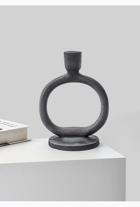 Close-up of matte black candle holder with circular ring design on a white surface