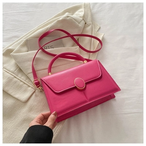 Détail d'un sac trapèze en cuir rose vif avec fermeture dorée et poignée ronde