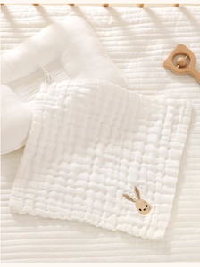 Detail of soft 6-layer cotton gauze baby bib with cute rabbit embroidery on white fabric