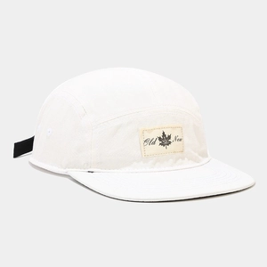 Detail of five-panel cream canvas camping hat with maple leaf patch and flat brim