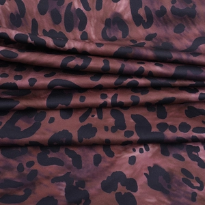 Gros plan détaillé du tissu à imprimé léopard rouge foncé avec des taches noires et plis