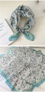 Flat lay of a floral cotton linen square scarf with teal borders and delicate patterns