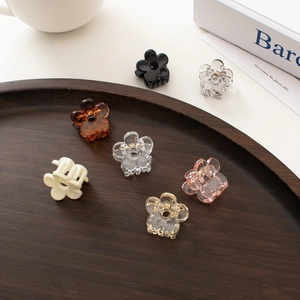 Close-up of seven mini flower hair clips in various colors arranged on a wooden plate