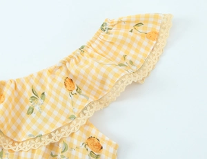 Dettaglio ravvicinato del tessuto a quadri giallo con stampa frutta e pizzo