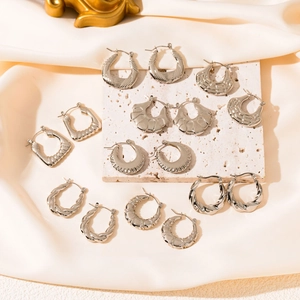 Minimalist silver hoop earrings with irregular geometric textures on silk and stone