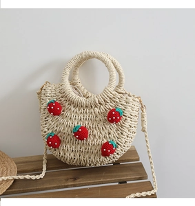 Detail der handgewebten Strohtasche mit süßen Erdbeeren aus Häkelarbeit auf einer Holzbank