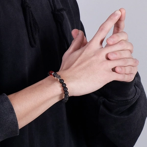 Lava stone bead bracelet featuring Hamsa Hand charm and red accent bead on wrist
