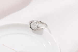 Dettaglio anello in argento S925 con inserto floreale in zirconia e incisione brand