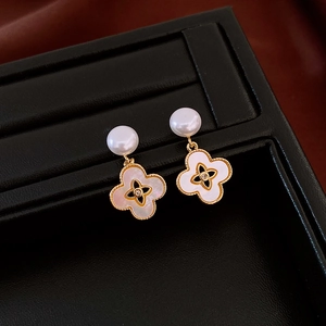 Close-up of mother-of-pearl clover earrings with pearls on black leather display