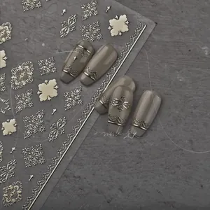 Detail of vintage embossed gold nail stickers with cross and lace patterns on gray nails