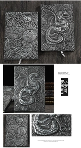 Macro detail of 3D embossed dragon notebook with silver metallic hard cover and silk ribbon
