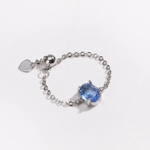 Macro shot of silver chain ring with oval blue zircon and heart-shaped metal pendant
