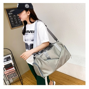 Model carrying a large grey travel bag with wet-dry separation for fitness or travel